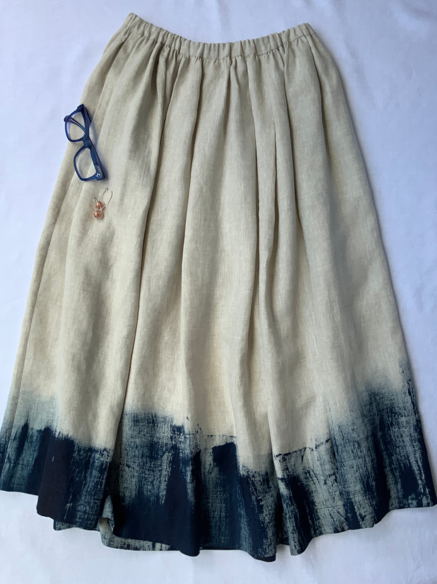 natural linen coloured skirt with elastic waist, lower calf length with dark navy rough painted hem