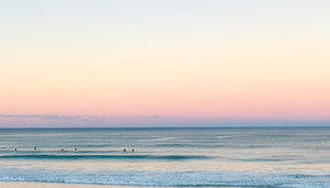 Surfers in winter sunset at Skennars Head Beach northern NSW. Beautiful soft pinks and blues