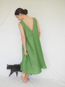 Woman wearing elegant green A-line summer linen ALBA dress with deep v-shaped back line. Side seam pockets with double looping self fabric belt (not shown). Australian made