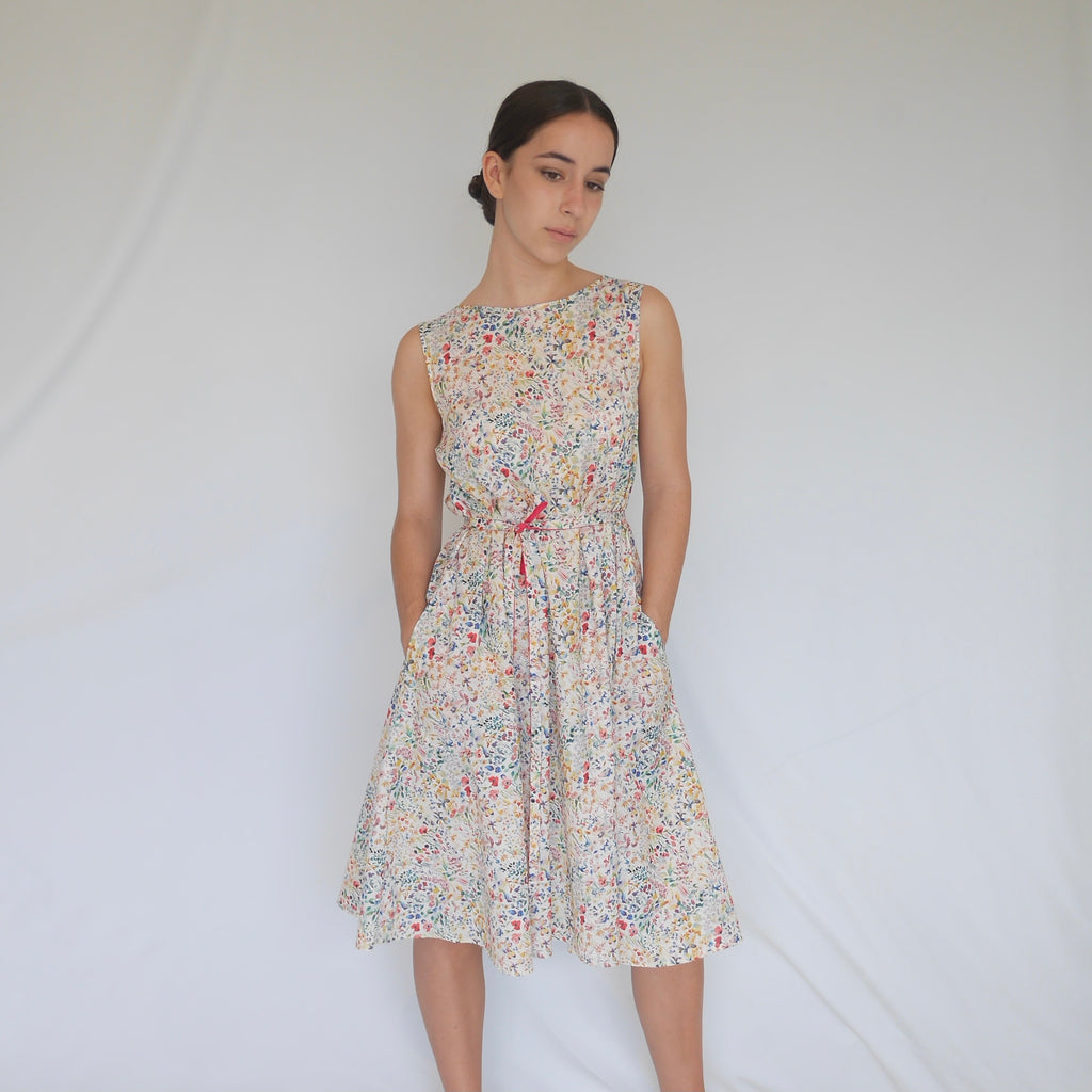 Woman wearing LUZ Liberty cotton A-line dress. Dress has side seam pockets, self fabric belt, low V-neck back. Australian made.