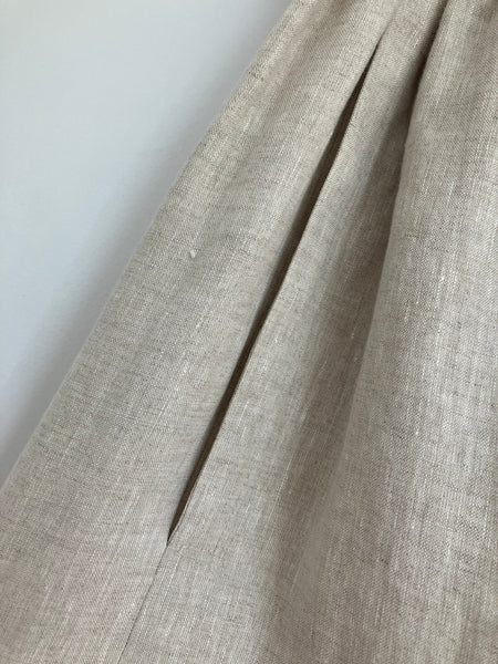 Pocket detail of natural linen coloured skirt with elastic waist, lower calf length with dark navy rough painted hem