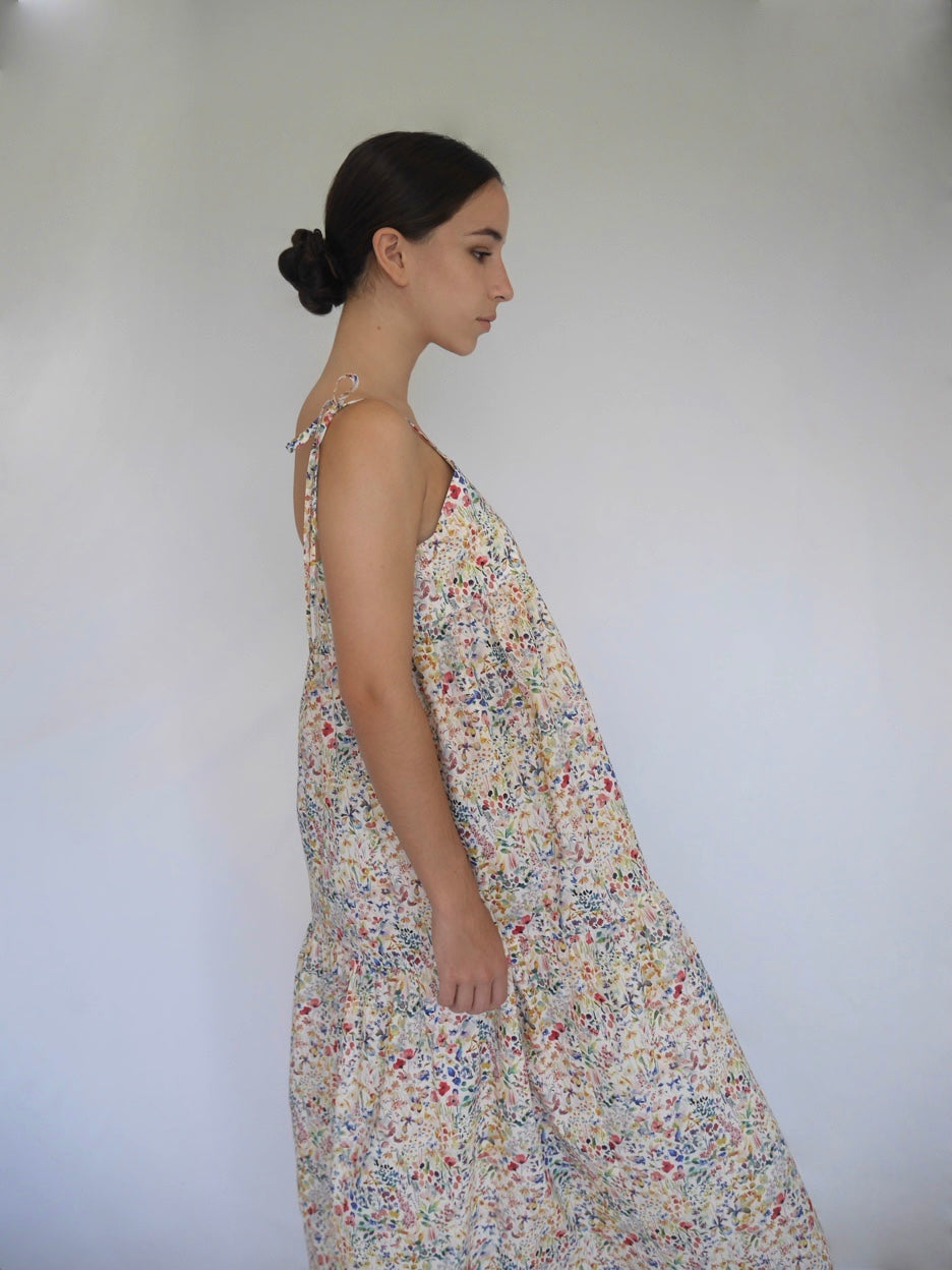 Corfu dress. Side view of woman wearing delicate tiered floral Liberty cotton shoe string strap summer dress Australian made