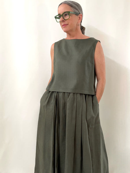 Person wearing a khaki linen sleeveless top and khaki skirt against a plain background