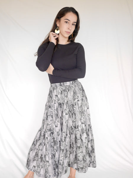 Woman wearing 3 tiered cotton black and white printed skirt, mid calf length, elastic waisted with voluminous hem