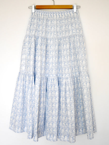 Hanging skirt front view  of 3 tiered cotton light blue and white printed skirt, mid calf length, elastic waisted with voluminous hem in Roman arches print