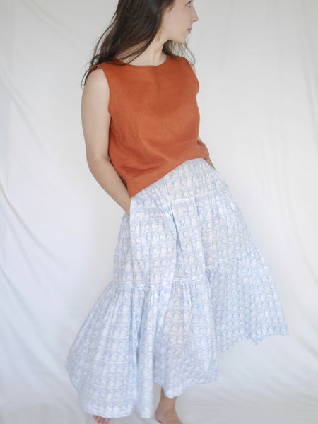 Woman wearing 3 tiered cotton black and white printed skirt, mid calf length, elastic waisted with voluminous hem in Roman arches print, hands in pockets