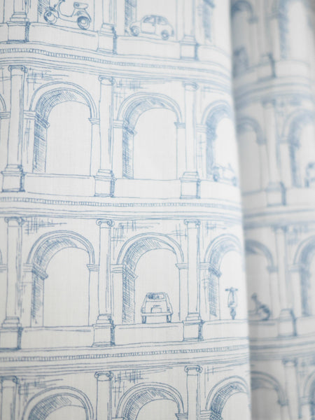 Close up of Liberty cotton fabric showing the Roman Arches fabric in light blue and white. Print uses fine pen drawing of arches, mopeds, and cars.