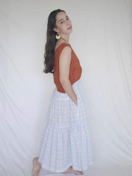 Woman wearing 3 tiered cotton black and white printed skirt, mid calf length, elastic waisted with voluminous hem in Roman arches print, hands in pockets