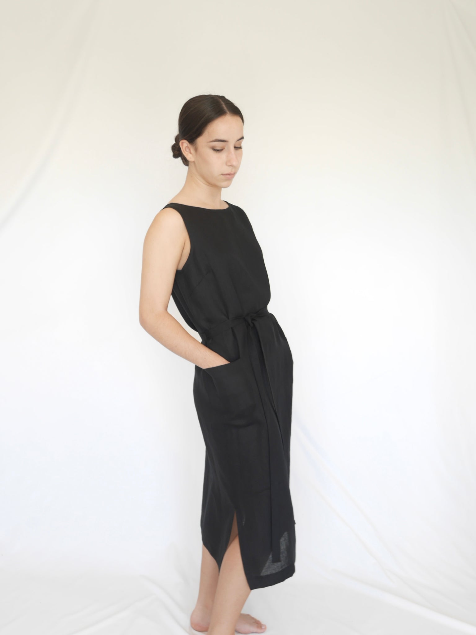 Black straight linen sleeveless mid calf length dress with front pockets, self tie belt, side splits, back opening   